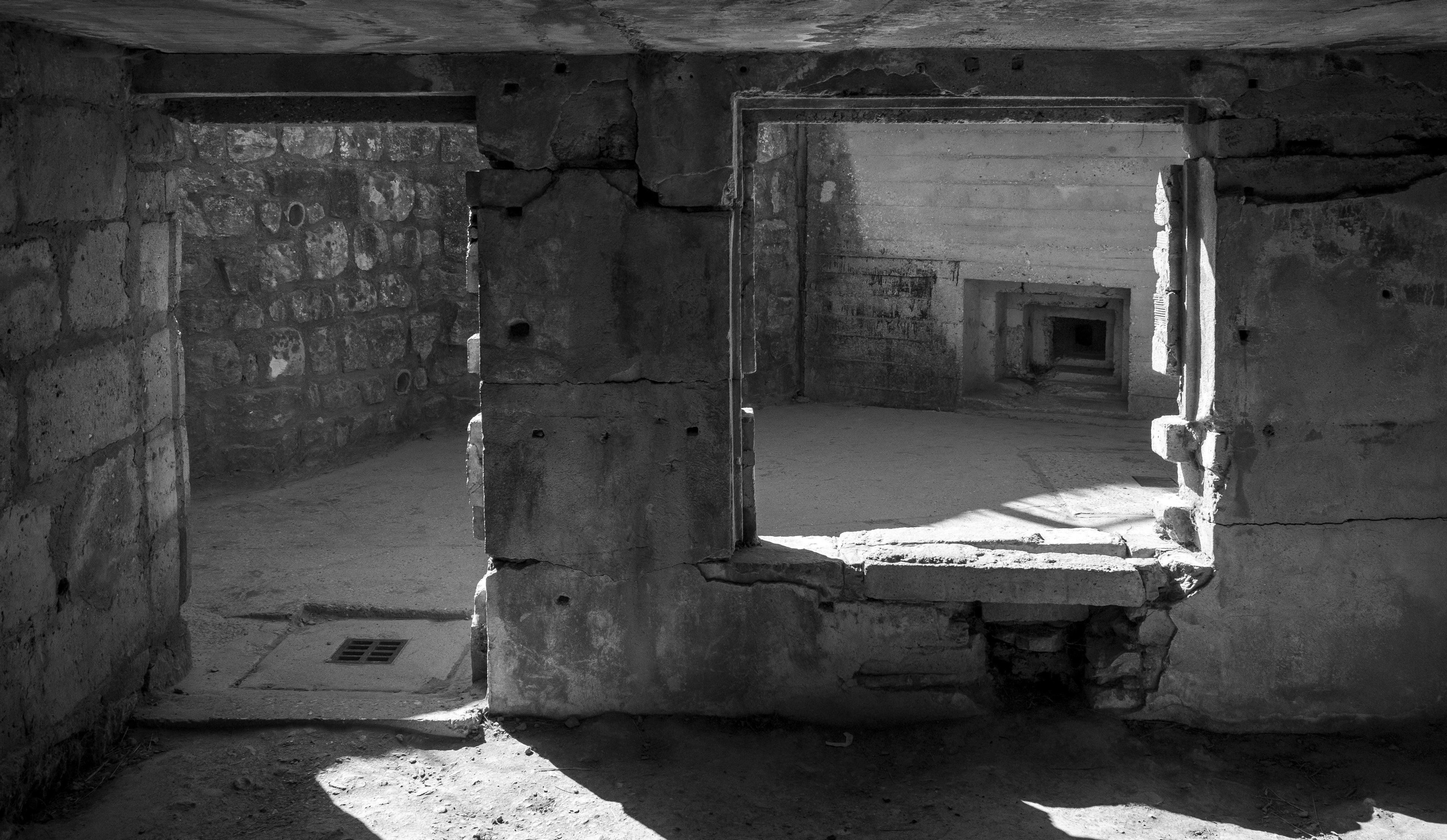 Interior of a German bunker at Pointe du Hoc, light through two embrasures and doorways receding into the dark