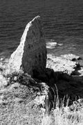 A limestone sea stack below the cliffs at Pointe du Hoc with dark water beyond, Normandy