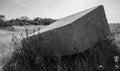 A huge tilted slab of German bunker concrete leaning in long grass at Pointe du Hoc, Normandy