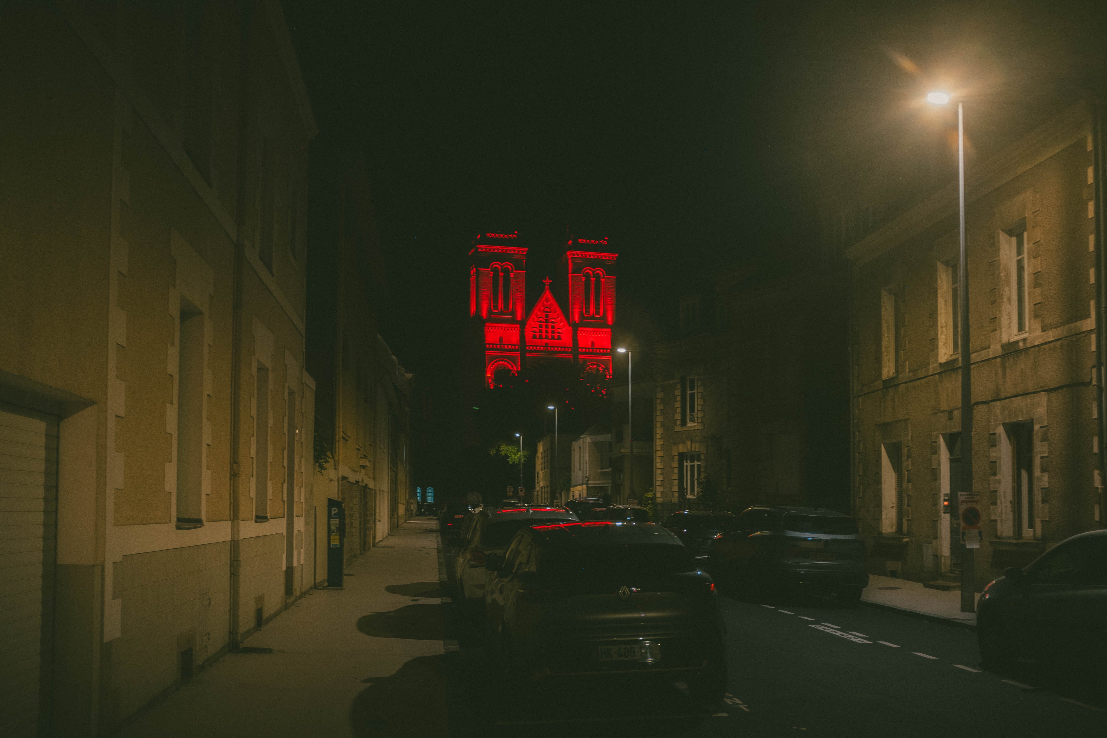 The twin towers of the Basilique Saint-Donatien in Nantes lit deep red against a black night sky