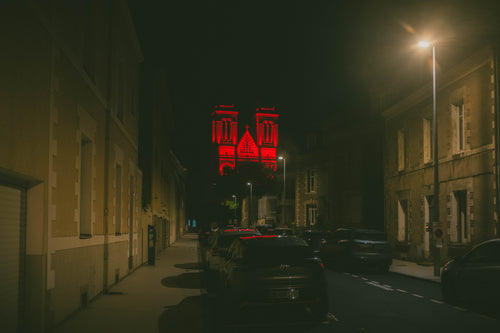 The twin towers of the Basilique Saint-Donatien in Nantes lit deep red against a black night sky
