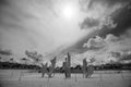 Anilore Banon's steel Les Braves sculpture on the sand at Omaha Beach with flags along the shoreline and the sun behind, Normandy, black and white