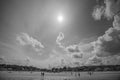 Omaha Beach at low tide under a high sun, four miles of empty sand with a handful of distant figures, black and white