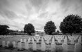 Rows of Commonwealth headstones running away towards the cemetery shelter and trees under heavy cloud, Ranville War Cemetery, Normandy