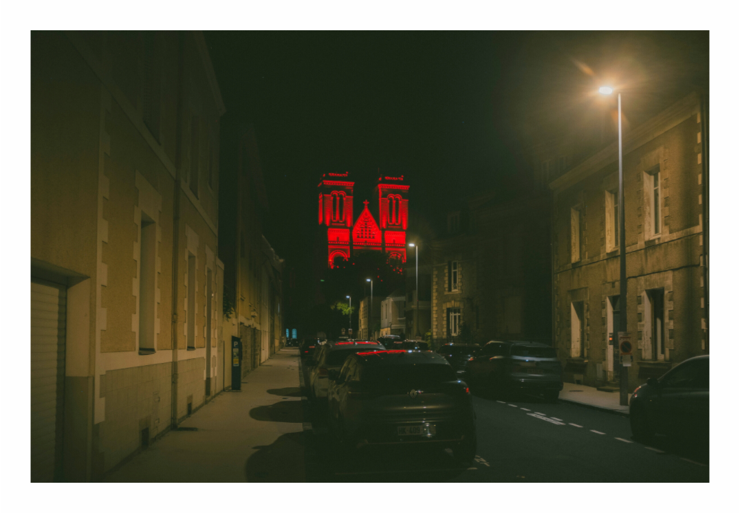 The twin towers of the Basilique Saint-Donatien in Nantes lit deep red against a black night sky