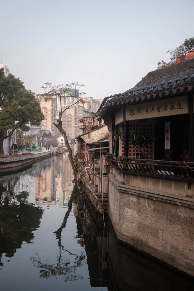 A stone canal in Shao Xing, China, its bridges and old houses held still on the water, black and white